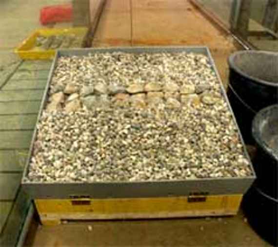 In der Kippvorrichtung sind große Steinen auf einem Kiesbett aufgelegt um den Reibungswinkel dieser Steine bestimmen zu können (Bei welcher Neigung des Kiesbettes beginnen sich die Steine zu bewegen und rutschen ab?).