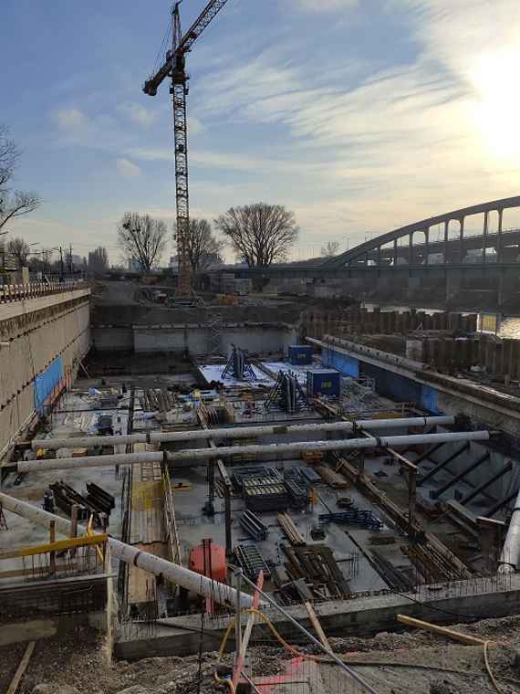 There are even more building materials on the foundation. On the far right the sun is looking through the clouds.