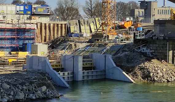 Three concrete walls at the banks of the Danube Canal forming two channels can be seen. In front runs the Danube Canal, behind it is the construction site. View from the other side of the Danube Canal.