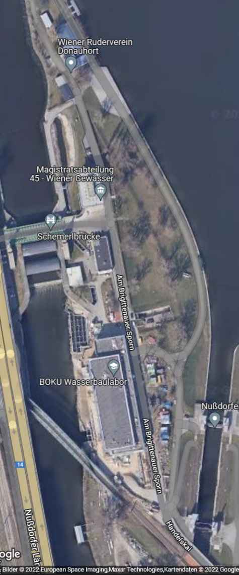 The image taken from a satellite shows the object, which is labeled "BOKU Wasserbaulabor", during the construction phase in early 2022. In the meantime, the building can be clearly seen from above. On the left side of the object, you can see the Danube Canal with the hydroelectric power plant Nußdorf, on the right side the Danube.