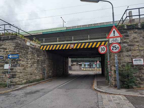 On the picture you can see a railroad bridge running across, below and in front of it runs the Sickenberggasse with a view to the institute, which can be seen small in the background. The signs warn of this as mentioned in the text on how to get to us with trucks.