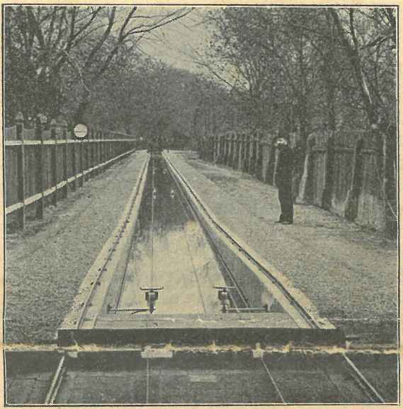 The picture taken at that time shows (according to the publication of the article at that time) a view from the station house, to the measuring canal. The facility was fenced all around with fences about 1.7 m high. Behind the fences to the left and right of the canal, you can see very tall trees. The tracks along the canal have a gradient at the beginning to reach the maximum speed very quickly. Above the water, two wires run parallel. A worker is standing to the right of the measuring channel.