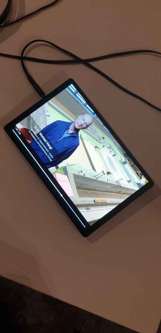 On a tablet you see Michael Hengl in a blue waistcoat. He is standing in front of a model test in our old hydraulic engineering laboratory in Severingasse.