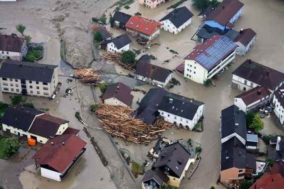 Photo: Village after being flooded by an extreme flood with large amounts of washed-up wood between the houses and large sludge deposits.