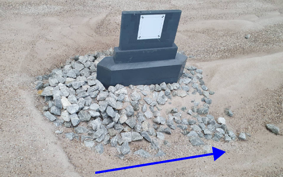 Large stones are lying on the riverbed around a bridge pier, preventing scour directly at the pier.