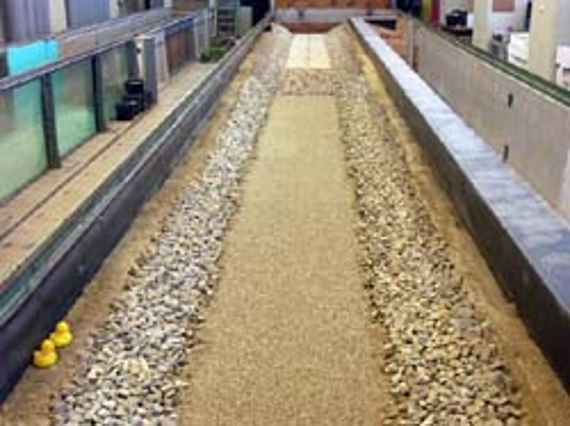 View of the physical model experiment (scale 1 to 20) - a straight channel with sand as riverbed and stones as bank protection.