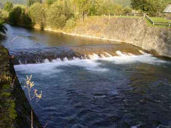 Bed sill on the Gail near Kötschach-Mauthen. The water flows over an approximately half meters high step. The river is bordered by walls on the left and right.