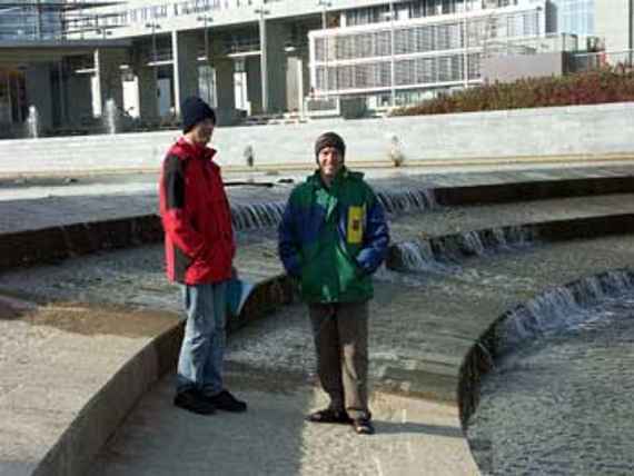 Graduate engineer Schaipp and Doctor Hengl on the threshold of the river Sohle in front of the government quarter in St. Pölten, in the background the buildings of the government quarter can be seen. Some water flows over the threshold of the river bed.