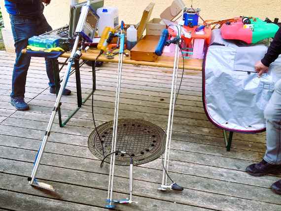 Auf einem Tisch sind mehrere Messgeräte ausgestellt, darunter drei stangenförmige Geräte für Punktmessungen sowie zwei Boote.