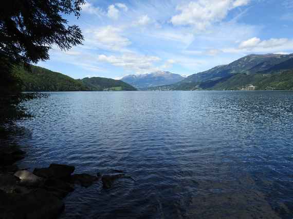 Das Foto zeigt einen großen See in Österreich, eingefasst von bewaldeten Hügeln und kleineren Siedlungen, ganz im Hintergrund in der Mitte ist ein hoher Berg zu sehen. Die Erfassung der Fischgemeinschaft eines großen Sees erfordert hohen Personal- und Arbeitseinsatz. eDNA-Methoden können hier in Zukunft evtl. unterstützend eingesetzt werden