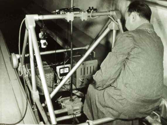 Ein schwarz-weißes Foto zeigt einen Mitarbeiter sitzend auf dem Messwagen samt technischen Ausrüstungen, die sehr viel Platz mittig auf dem Messwagen beanspruchten.