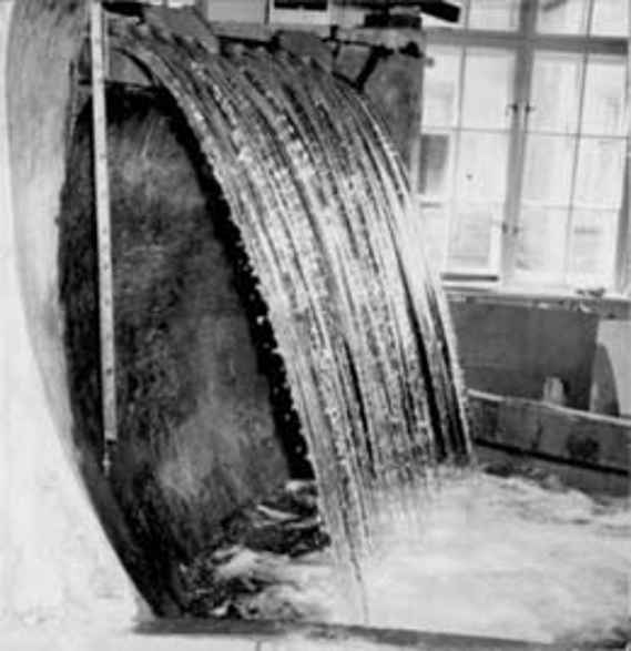 Das Bild zeigt eine Staumauer im Institut als Modell in schwarz/weiß. Das Wasser strömt von oben nach unten. Im Hintergrund ist ein Fenster zum Hof.