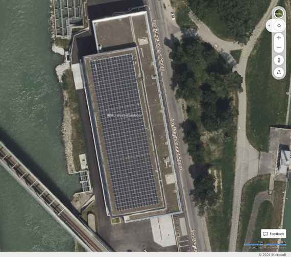 Auf dem Screenshot als Satellitenbild sieht man die Solarzellen auf dem Dach. Links verläuft Donaukanal parallel, quer darüber schräg eine Eisenbahnbrücke. Rechts ist die Wiese, dazwischen Straße.