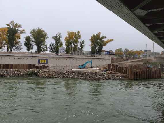 Donaukanal verläuft quer, gegenüber sieht man die längst hochgezogene Wand, oben drüber verläuft Eisenbahnbrücke.