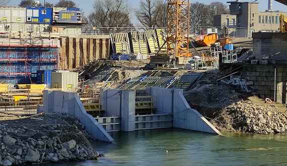 Drei Betonmauern stehen am Ufer des Donaukanals und bilden zwei Kanäle. Dahinter befindet sich die Baustelle. Blick von der anderen Seite des Donaukanals.