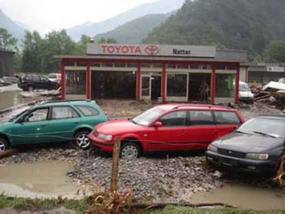 Ein Autohaushandel, vorne 3 Autos und dahinter links und rechts einige Autos bei Geschiebeablagerung auf dessen Parkplatz.
