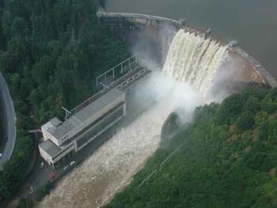 Luftbild zeigt den Staudamm Ottenstein beim Katastrophenhochwasser im August 2002, wobei das Wasser von oben nach unten strömt. Links daneben das Kraftwerk. Dahinter und an gegenüberliegendem Ufer Wald.