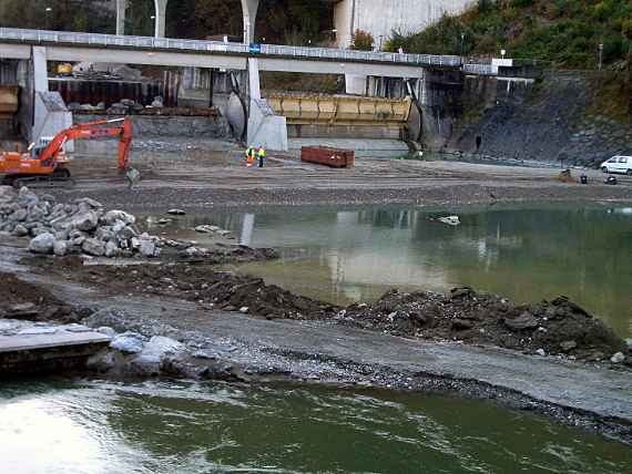 Wehranlage in der Bauphase, links ein Weg zum im Hintergrund stehenden Bagger, dahinter in Bau befindete Schleuse. Davor liegt noch Wasser.