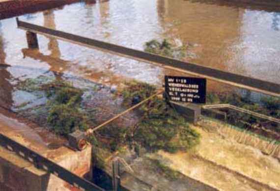 Untersuchung der Verklausung mit Treibgut im physikalischen Modell, man sieht die Überfallwehre im Detail, die durch Treibgut verlegt sind. Zweige verstopfen den Außlassbereich des Stausees und der Hochwasserabfluss kann nur schlecht abrinnen.