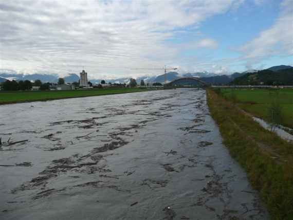 Auf Bild sieht man einen Fluss nach einem Hochwasser, links und rechts Ufer bei etwas bewölktem Wetter.