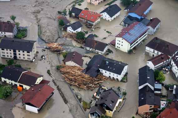 Ortschaft nach der Überflutung durch ein extremes Hochwasser mit großen Mengen an angeschwemmten Holz zwischen den Häusern und großen Schlammablagerungen.