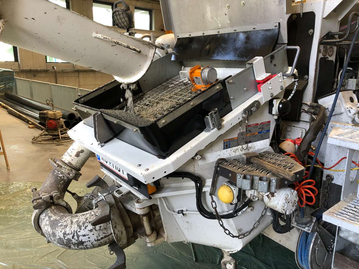 The concrete flows through a chute into a collection basin of the car with the concrete pump. Below you can see a pipe through which the concrete is pumped.