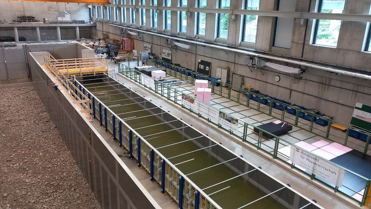 View into the MainChannel from a height of about 5 meters. There are three channels visible. In the left channel a gravelled bed can be seen, in the middle channel there is water. The right channel of the Institute for Hydraulic Engineering and Hydrometry is under construction.