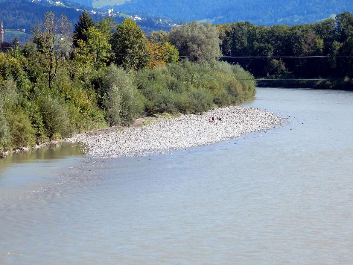 Photo shows four peoples use a gravel bank of the river to relax.