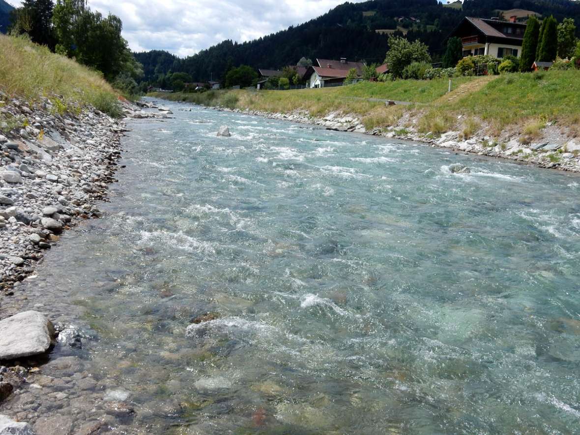 The first picture shows the very straight river and the banks covered with grass. The second picture shows a bridge over the river. The third picture shows the flow measuring point (gauge) located directly below the bridge. At the gauge house there is a display board with the following information: Water level = thirty-three centimeters, flow rate = six point two cubic meters per second, water temperature twelve point two degrees Celsius, air temperature twenty-three point two degrees Celsius.