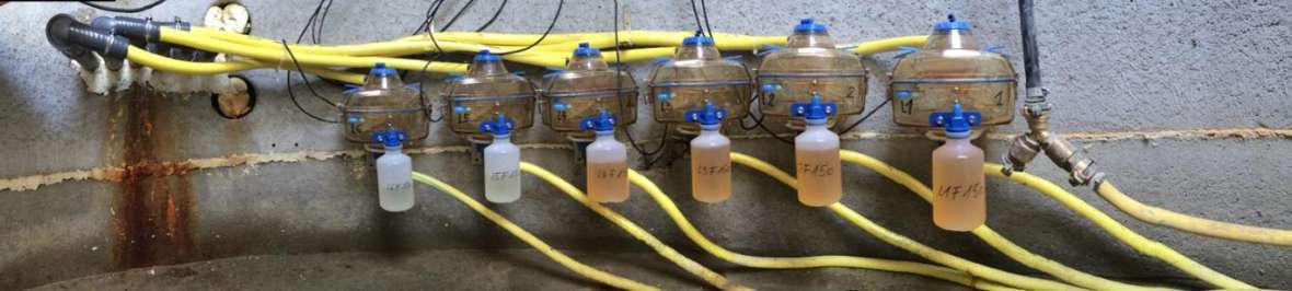 In the picture, you can see six tipping bucket gauges for the collection of seepage water and six plastic bottles that collect the seepage. Yellow hoses connect the measuring devices.
