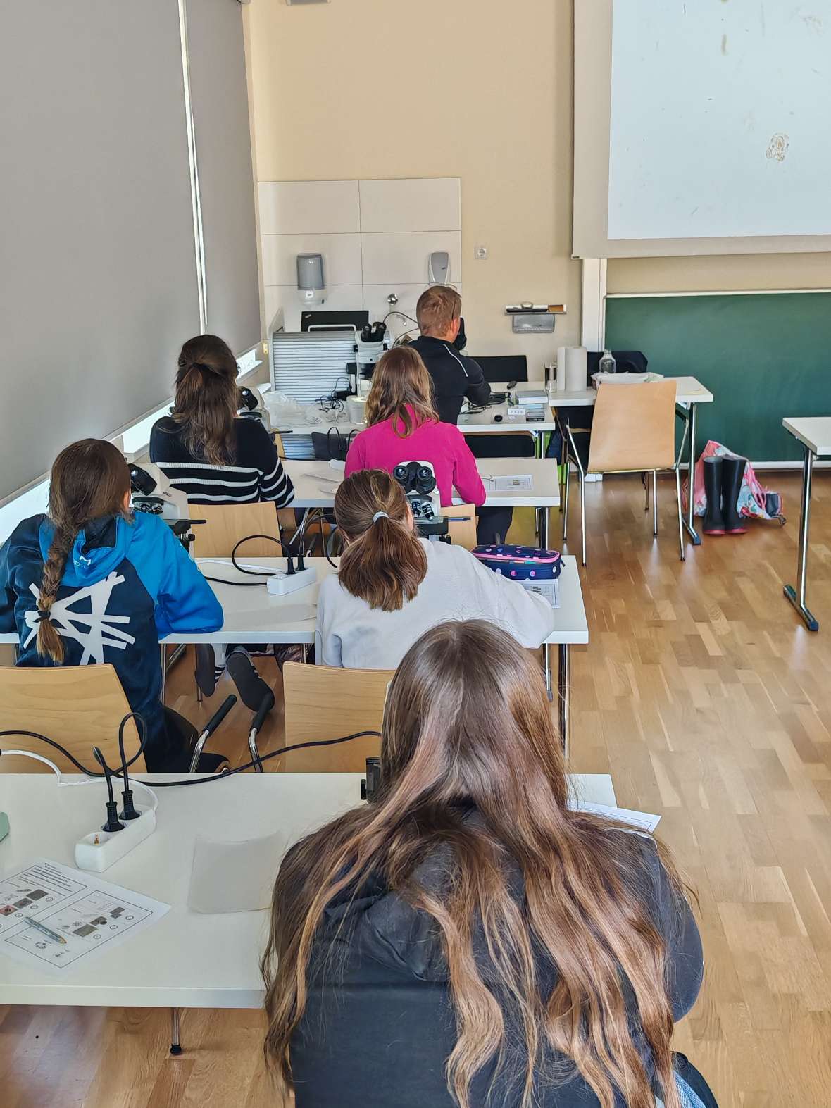 IGF: Die Mädchen sitzen im Lehrsaal an Tischen und blicken auf eine Projektionsfläche an der Wand.