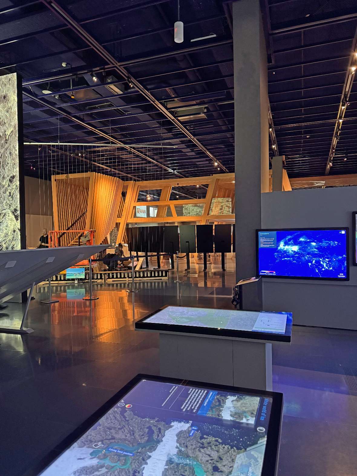 Ars Electronica: Innenraum eines modernen Museums mit interaktiven Bildschirmen und einer großen Holzstruktur im Hintergrund