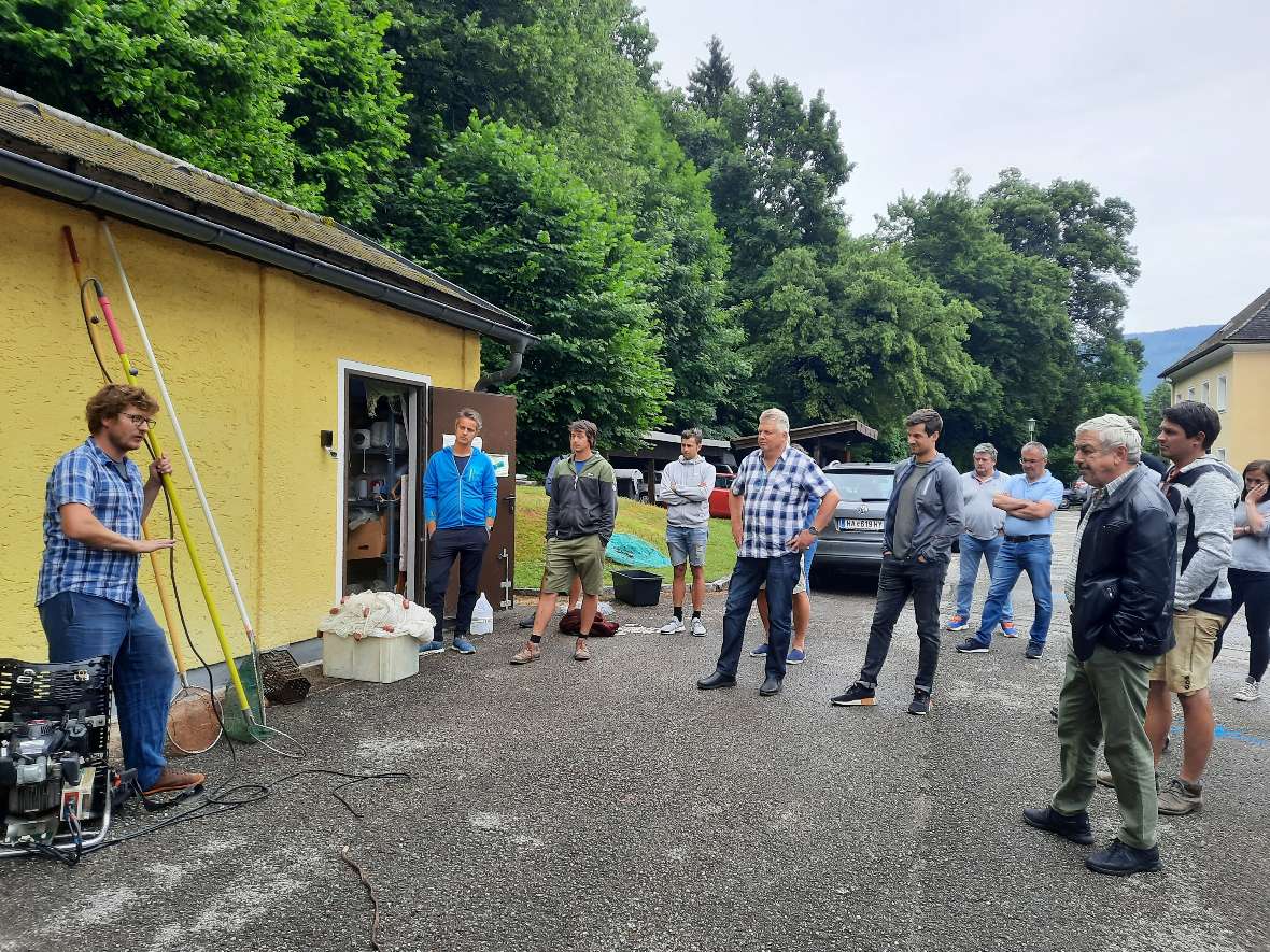 Den Teilnehmern wird auf einer Wiese die große Flügelreuse gezeigt. 