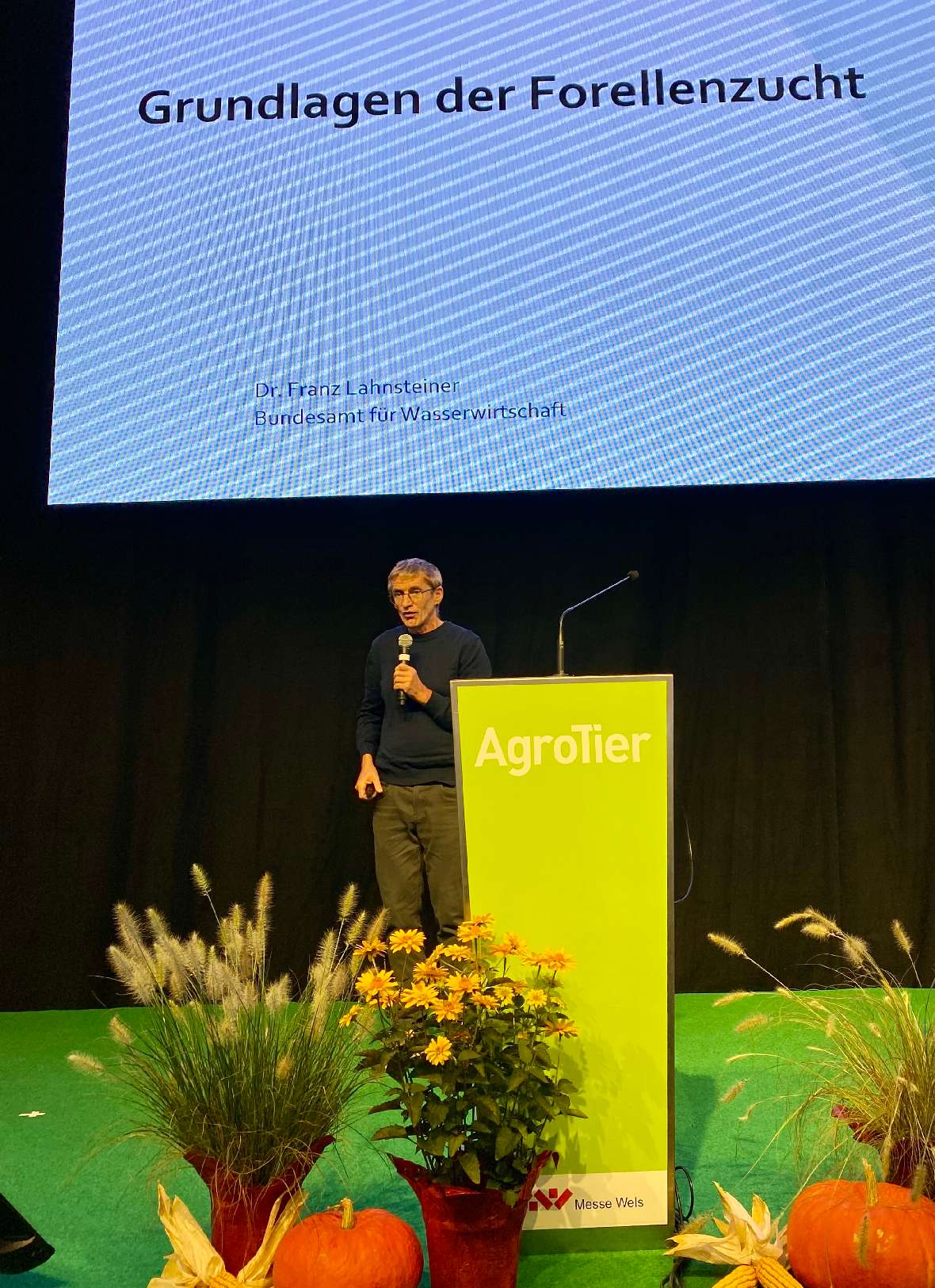 BAW-Mitarbeiter Franz Lahnsteiner auf der Bühne beim präsentieren "Grundlagen der Forellenzucht".