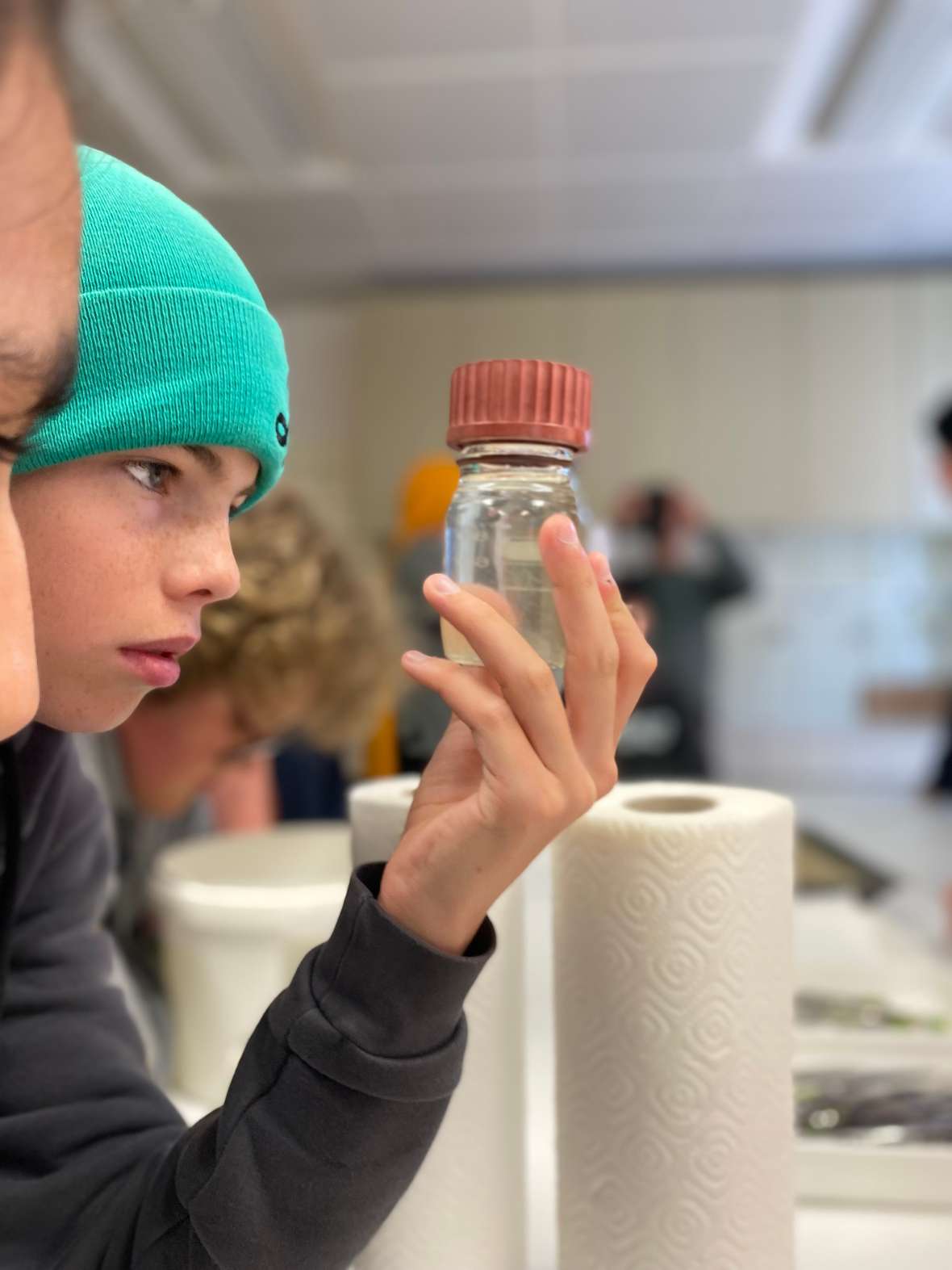 Ein Schüler beim Begutachten von Plankton in einem Glasgefäß.