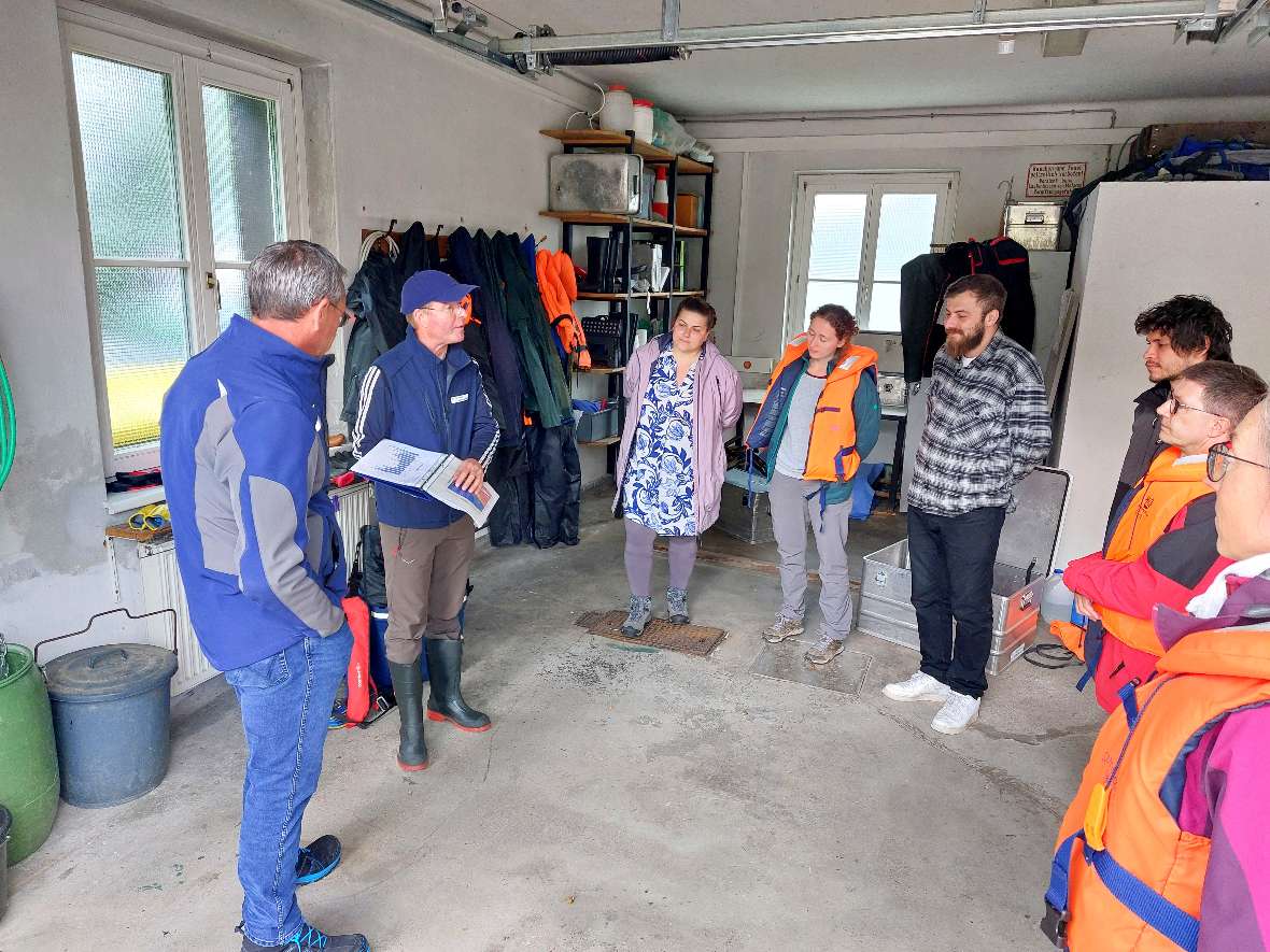 Abteilungsleiter der Seenkunde Martin Luger und die Teilnehmer:innen bei Vorbesprechung bevor es aufs Boot geht. 