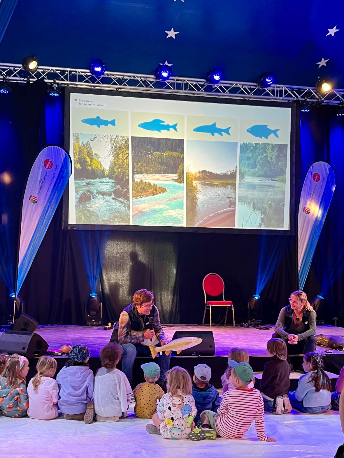 Mitarbeiter Florian Keil erklärt den Kindern anhand von Fisch-Stofftieren die verschiedenen Fischarten.