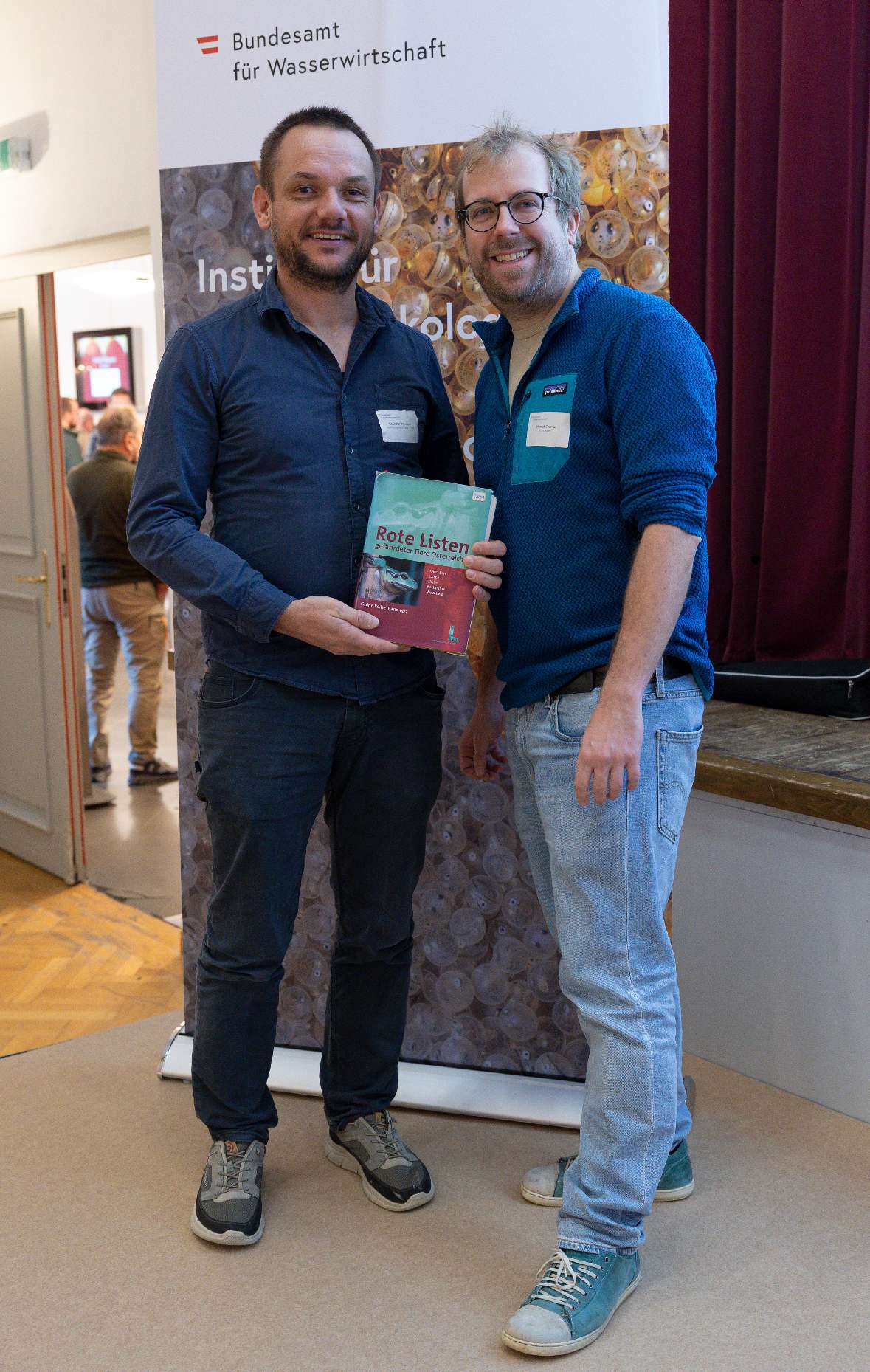 Clemens Ratschan und Thomas Friedrich stehen nebeneinander und präsentieren die neue Liste "Rote Fische". Im Hintergrund ein Banner mit dem Logo des Bundesamts für Wasserwirtschaft.