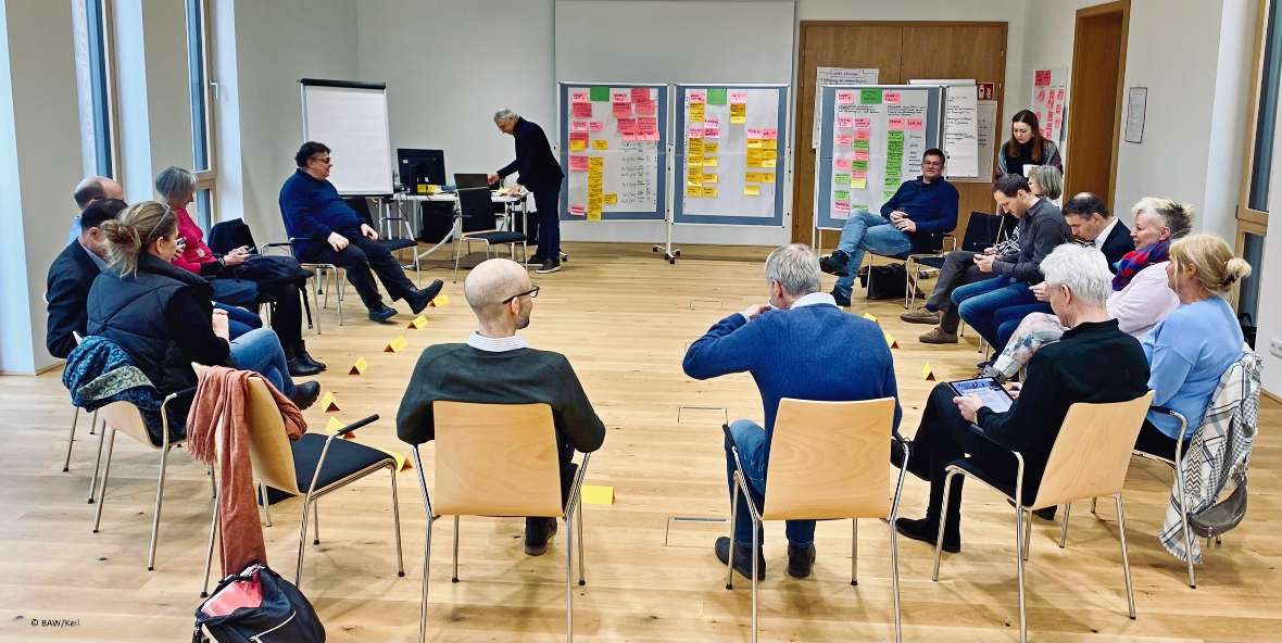 Die Teilnehmer:innen der Sektionsklausur im Lehrsaal. Man sieht Flipcharts mit vielen bunten Zetteln drauf. 