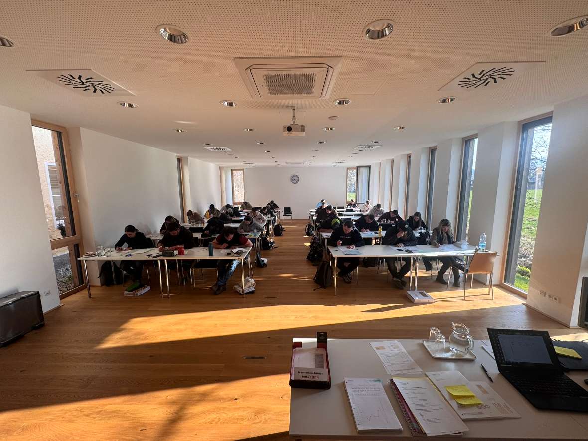 Die Teilnehmer:innen sitzen im Saal und absolvieren die Abschlussprüfung.