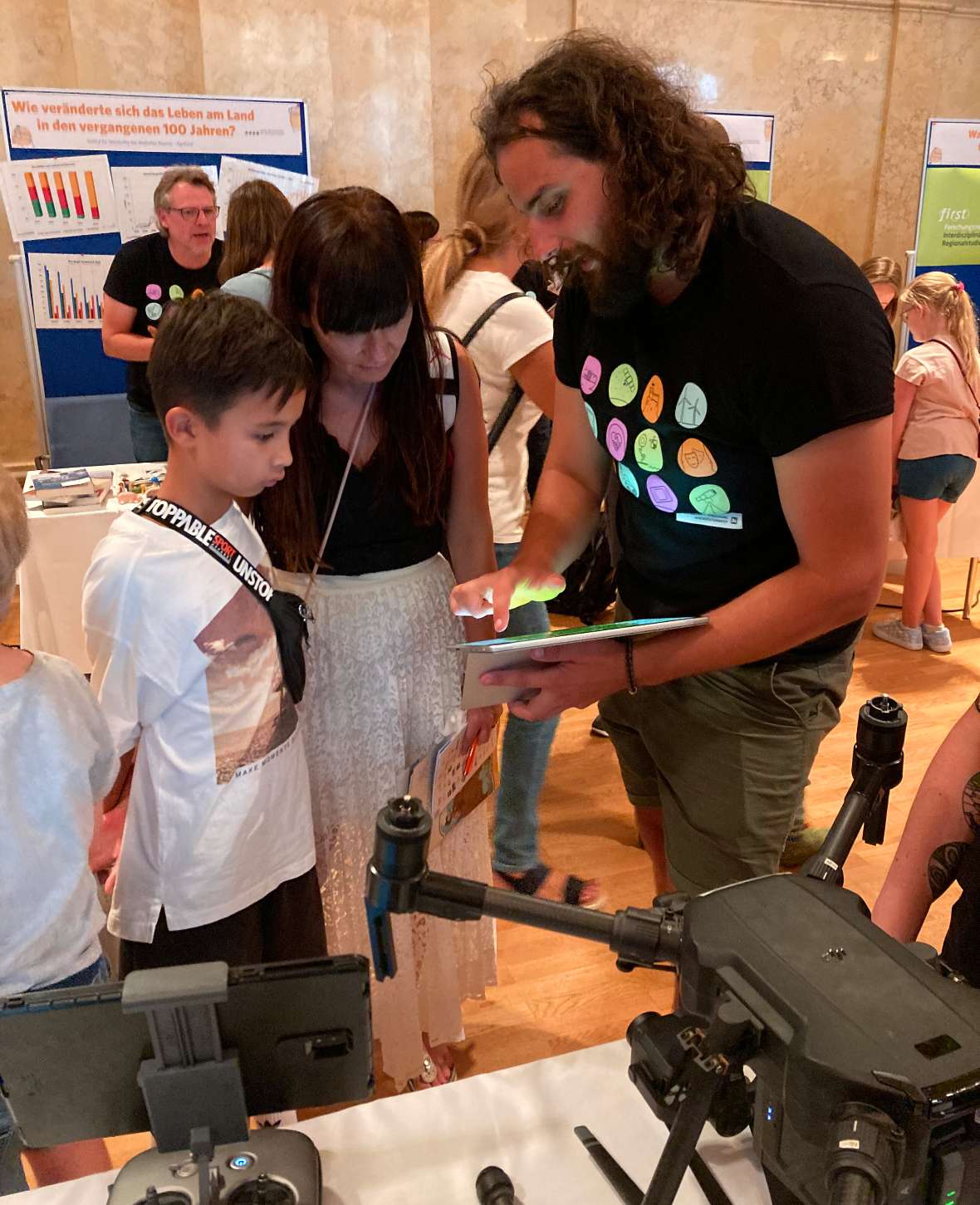 Mitarbeiter Matthias Konzett erklärt den neugierigen Besuchern, auf eine Tablet, wie die Bestimmung der Pflanzenvitalität funktioniert.