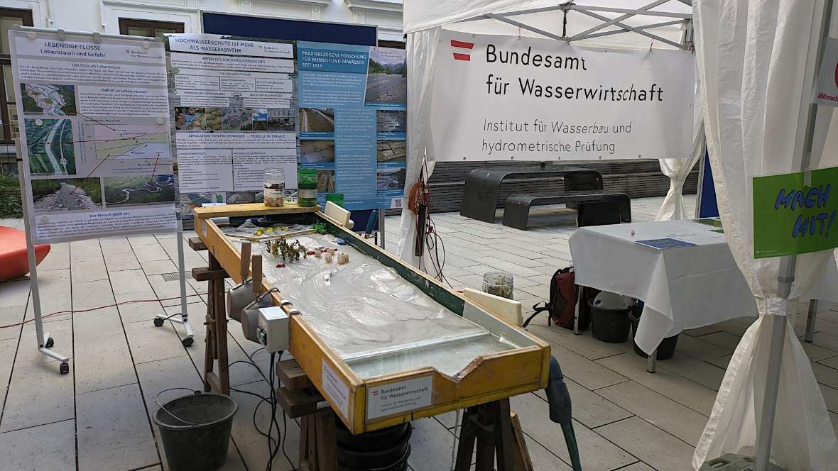 Hier sieht man den linken Teil unseres Info-Standes mit drei Poster im Hintergrund. Im Vordergrund steht unser kleiner Modellfluss, der etwa 2 Meter lang und 1 Meter breit ist.