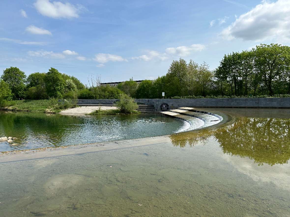Das Wasser des Flusses Traisen fließt über 3 Stufen. Auf der anderen Seite des Flusses stehen Bäume und Sträucher.