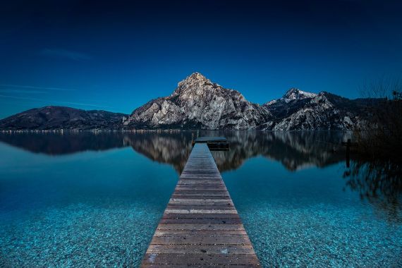 Ein langer Steg führt in den Traunsee. Der Traunstein im Hintergrund.