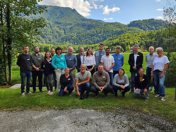 Gruppenfoto der Teilnehmer:innen am SIL-Austria Meeting 2025. Im Hintergrund sieht man Bäume und einen Berg.