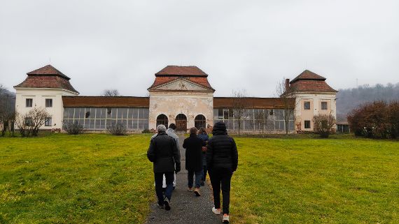 Im Bild ist ein Teil des Klosterziergartens zu sehen. Vier Personen gehen auf das von Überschwemmungen bedrohte Prämonstratenserkloster in Jasov zu.