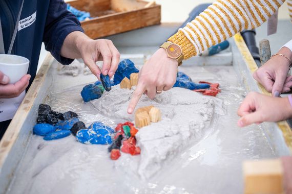 Am Flussmodel konnten die Teilnehmer:innen die Entwicklung eines Flusses beobachten, selbst lenkend eingreifen und die Kraft des Wassers erleben.