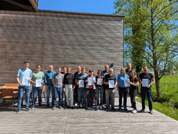 Gruppenbild mit 16 Personen, von denen einige ein Zertifikat in der Hand halten.