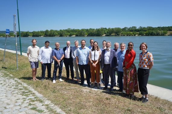 Gruppenfoto mit 14 Personen, im Hintergrund ist die Donau zu sehen.